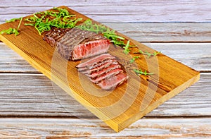 Medium rare beef sirloin with arugula on cut board