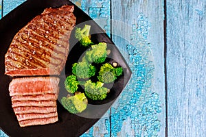 Medium rare beef sirloin with broccoli on black plate