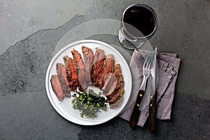 Medium rare beef steak on white plate, glass of red wine