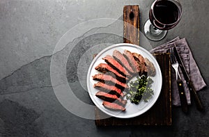 Medium rare beef steak on white plate, glass of red wine