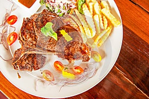 Medium rare Grilled T-Bone Steak served on white plate