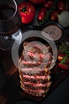 Medium rare meat rib eye steak slices in pan on chopping wooden