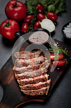 Medium rare meat rib eye steak slices in pan on chopping wooden