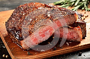 Medium Rare Ribeye steak on wooden board, selected focus