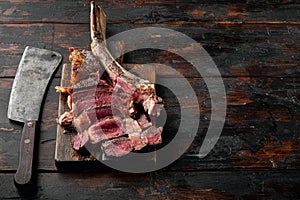 Medium rare Tomahawk meat marbled dry aged beef grilled, on wooden serving board, on old dark  wooden table background, with copy