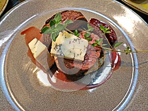 medium-rare veal mignon steak with pieces of dor blue cheese and plum sauce