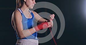 Medium shot. Beautiful female boxer wraps red bandages on hands. steadicam shot