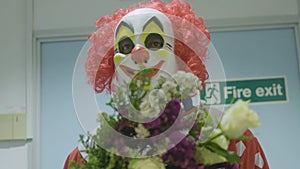 Medium shot of a clown holding a flowers