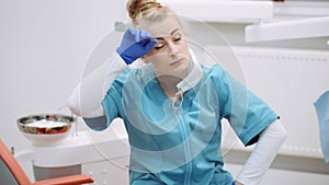 Medium shot of exhausted dentist sitting at chair