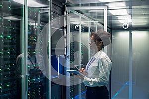 Female technician works on a tablet in a data center photo