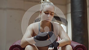 Medium shot of focused woman rolling bandage on hand in gym