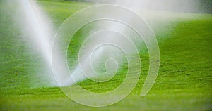 Medium shot of grass sprinkler splashes water over the lawn