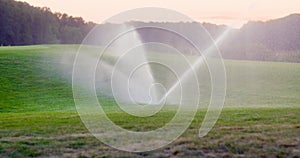 Medium shot of grass sprinkler splashes water over the lawn