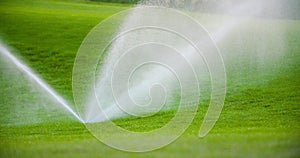 medium shot of grass sprinkler splashes water over the lawn