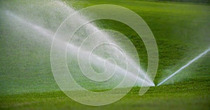 medium shot of grass sprinkler splashes water over the lawn