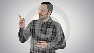 Handsome young man walking and looking to the camera and pointing to the sides showing something on gradient background.