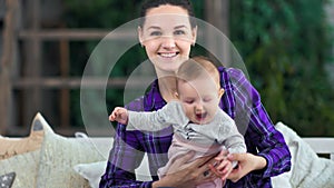 Medium shot happy young mother posing with little cute baby smiling looking at camera