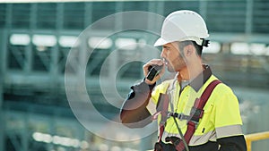 Medium shot of male professional engineer wearing hard hat talking using walkie talkie