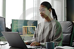 Middle Eastern Female Programmer Using Laptop Sitting at Workstation in Office