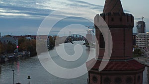 Medium Shot of Oberbaum Bridge Tower in Berlin, Germany rising up revealing Cityscape Skyline with TV Tower and Spree