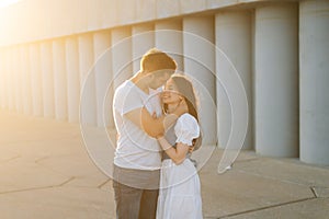 Medium shot portrait of cheerful romantic young couple in love hugging while man touching neck of girlfriends with hand.