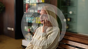 Medium shot portrait of focused serious blonde businesswoman talking on mobile phone in restaurant. Beautiful woman