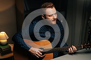 Medium shot portrait of guitarist singer man emotionally singing into condenser microphone and playing acoustic guitar