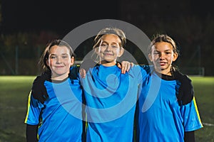 medium shot of three young girls in football blue sportswear taking a photo together