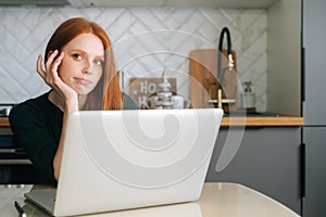 Medium shot of tired young woman office worker unmotivated and disinterested in dull work with laptop.