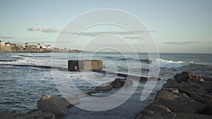 Medium shot of the waves hitting the stone shore at the Atlantic coast beach in Estoril, Cascais. 4k footage