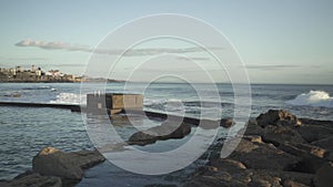 Medium shot of the waves hitting the stone shore at the Atlantic coast beach in Estoril, Cascais. 4k footage