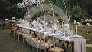 Medium shot of wedding table outdoor served and decorated with candles and dried and pastel flowers for boho style