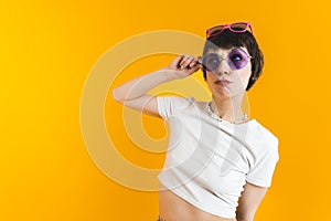 Medium shot of a woman in white top wearing two pairs of sunglasses - one on her nose and another on the top of her head