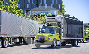 Medium-sized rig semi truck with box trailer turns on the city street towards a warehouse