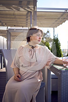 medium sized woman in peach fuzz dress with glass of water in restaurant