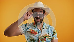 Medium studio shot of a latin charming surprised man in a light-colored hat and a vacation shirt taking of his