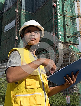 Medium vertical view Asian architectural engineer looking offscreen with background building