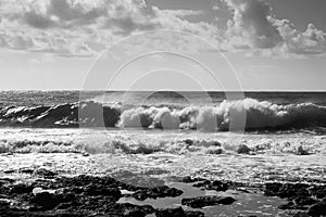 Medium waves crashing on the rocks, grey sky with clouds