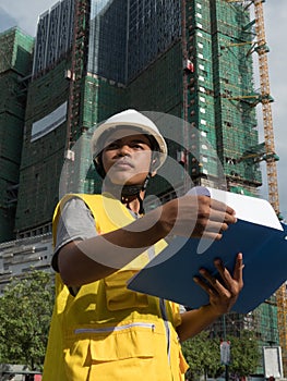 Medium wide vertical view Asian architectural engineer looking offscreen with background building