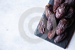 Medjoul dates on a black slate board on a gray background. Top view, copy space