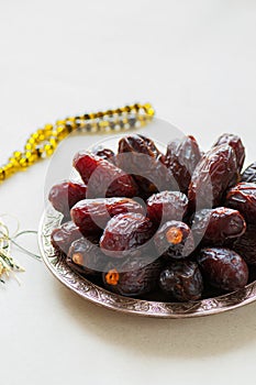 Medjoul - dried dates or kurma in a vintage plate and rosary