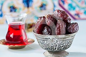 Medjoul kurma in a vintage bowl and glass of turkish tea