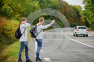 Meet New People. Looking for transport. twins walking along road. stop car with thumb up gesture. hitchhiking and