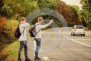 Meet New People. Looking for transport. twins walking along road. stop car with thumb up gesture. hitchhiking and