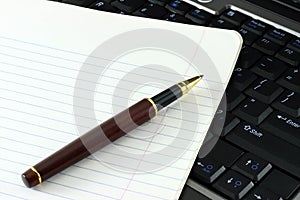 Notebook and pen on computer