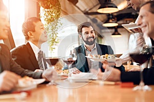 People sit at table eating sushi and drinking wine photo