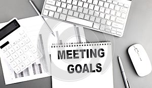 MEETING GOALS text written on notebook on grey background with chart and keyboard, business concept