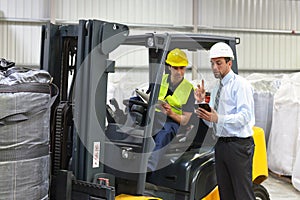 meeting of the manager and worker in the warehouse - forklift and interior of the industrial building