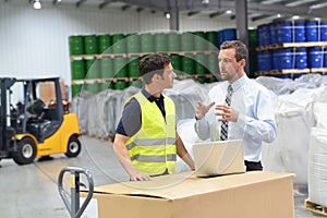 meeting of the manager and worker in the warehouse - forklift and interior of the industrial building