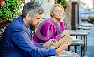 Meeting people with similar interests. Man and woman sit cafe terrace. Girl interested what he reading. Literature